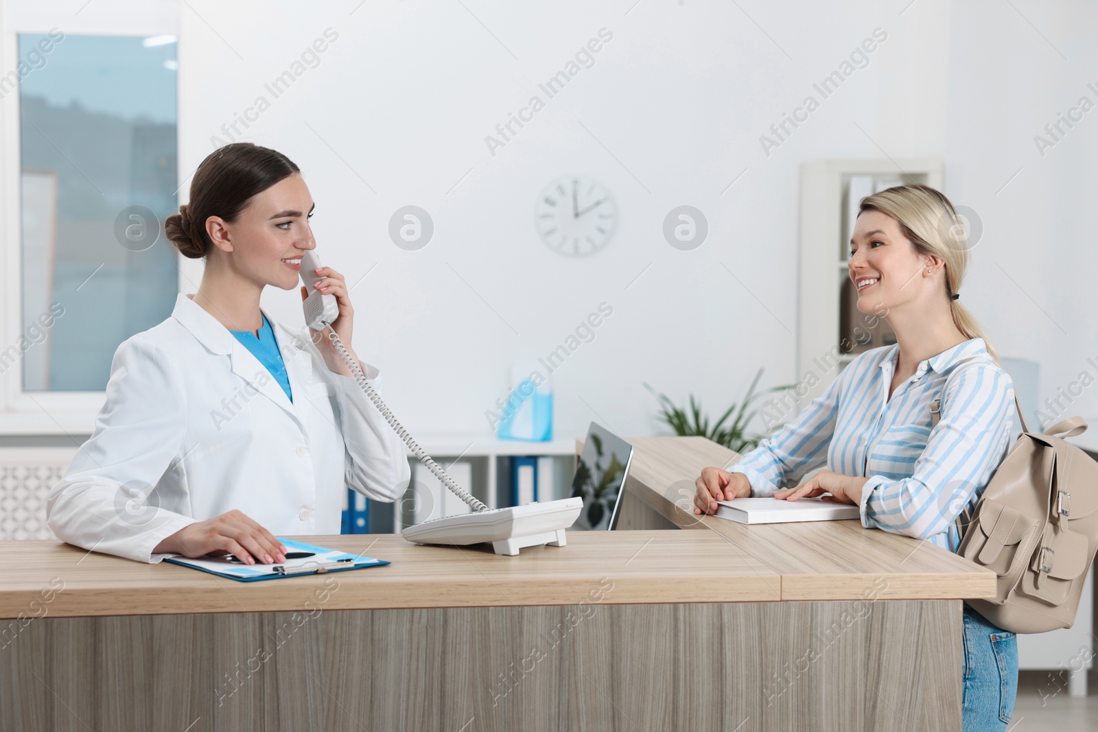 Photo of Professional receptionist working with patient at wooden desk in hospital