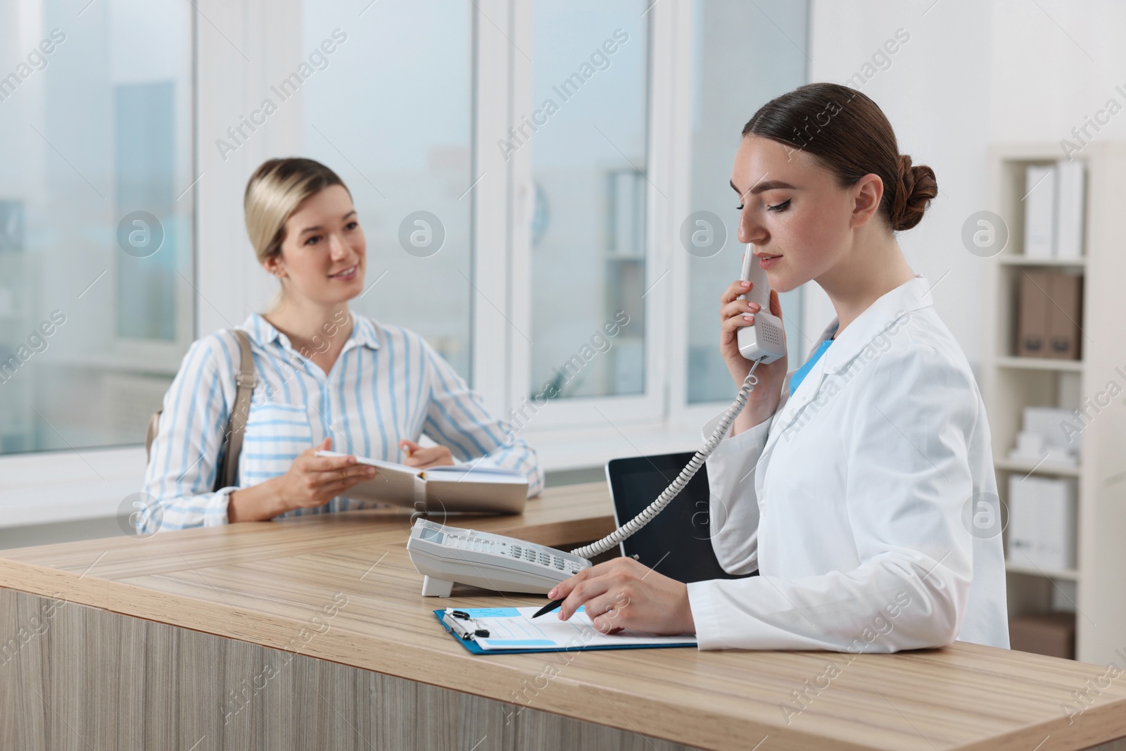 Photo of Professional receptionist working with patient at wooden desk in hospital