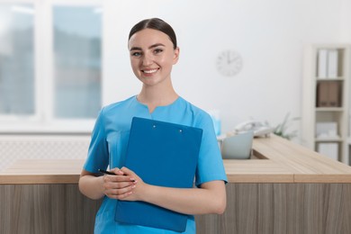 Professional receptionist with clipboard working in hospital