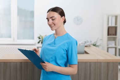 Photo of Professional receptionist with clipboard working in hospital