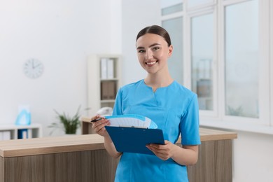 Professional receptionist with clipboard working in hospital