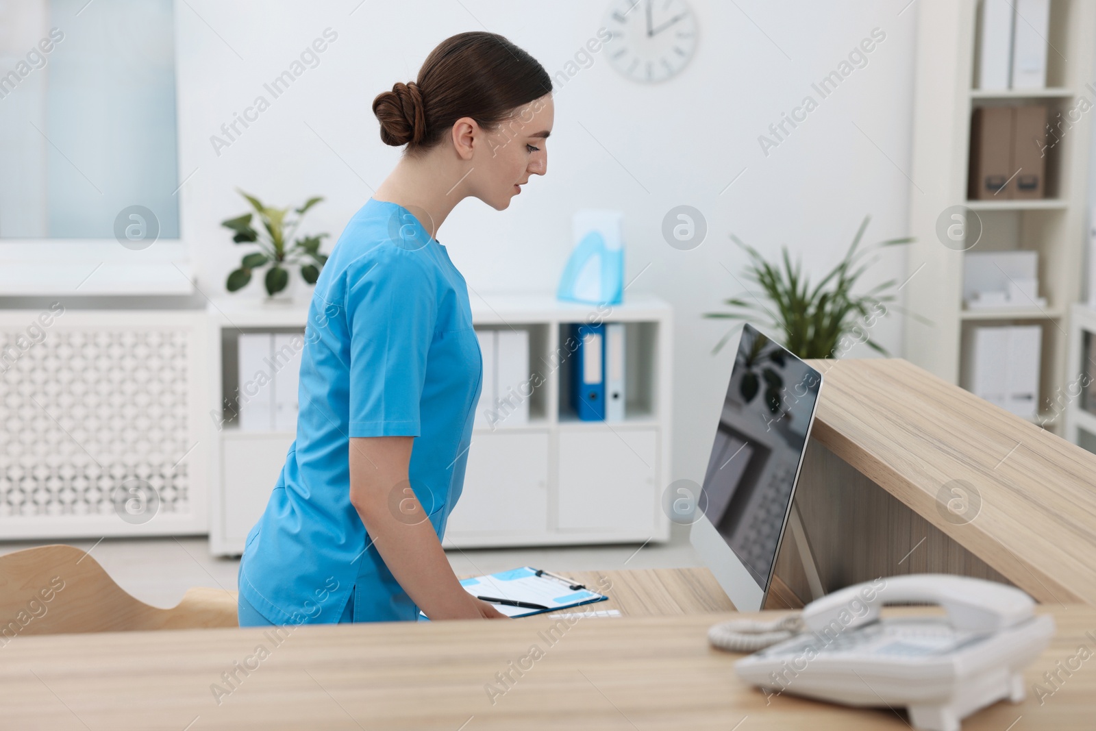 Photo of Professional receptionist working at wooden desk in hospital