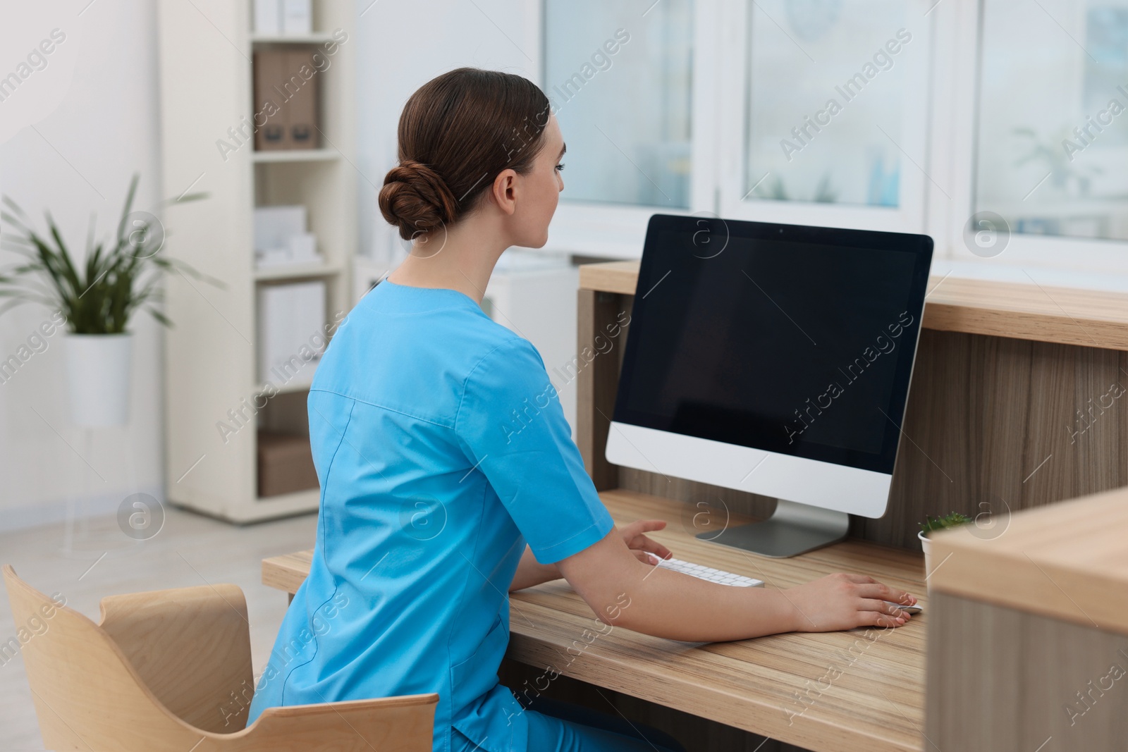 Photo of Professional receptionist working at wooden desk in hospital