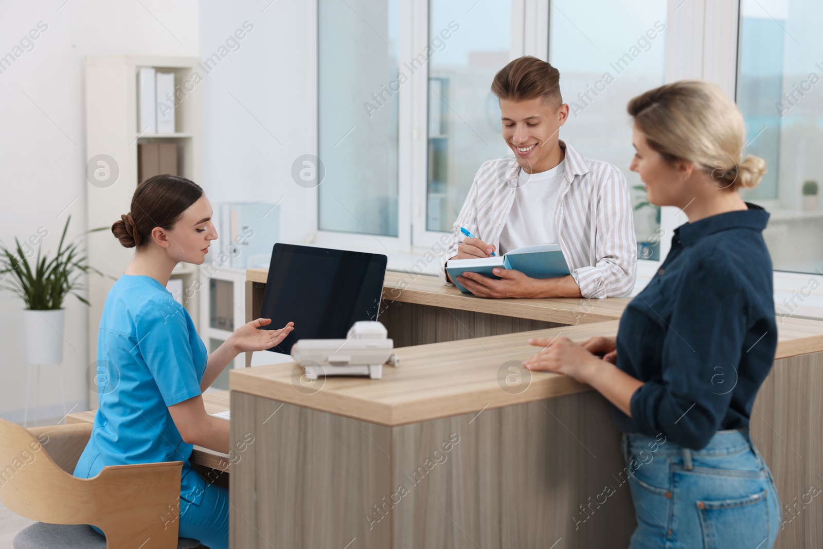 Photo of Professional receptionist working with patients at wooden desk in hospital