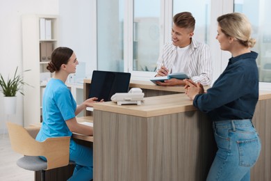 Photo of Professional receptionist working with patients at wooden desk in hospital