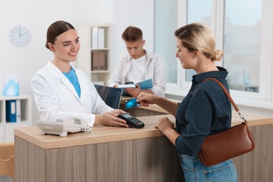 Photo of Receptionist taking payment from client via terminal at hospital