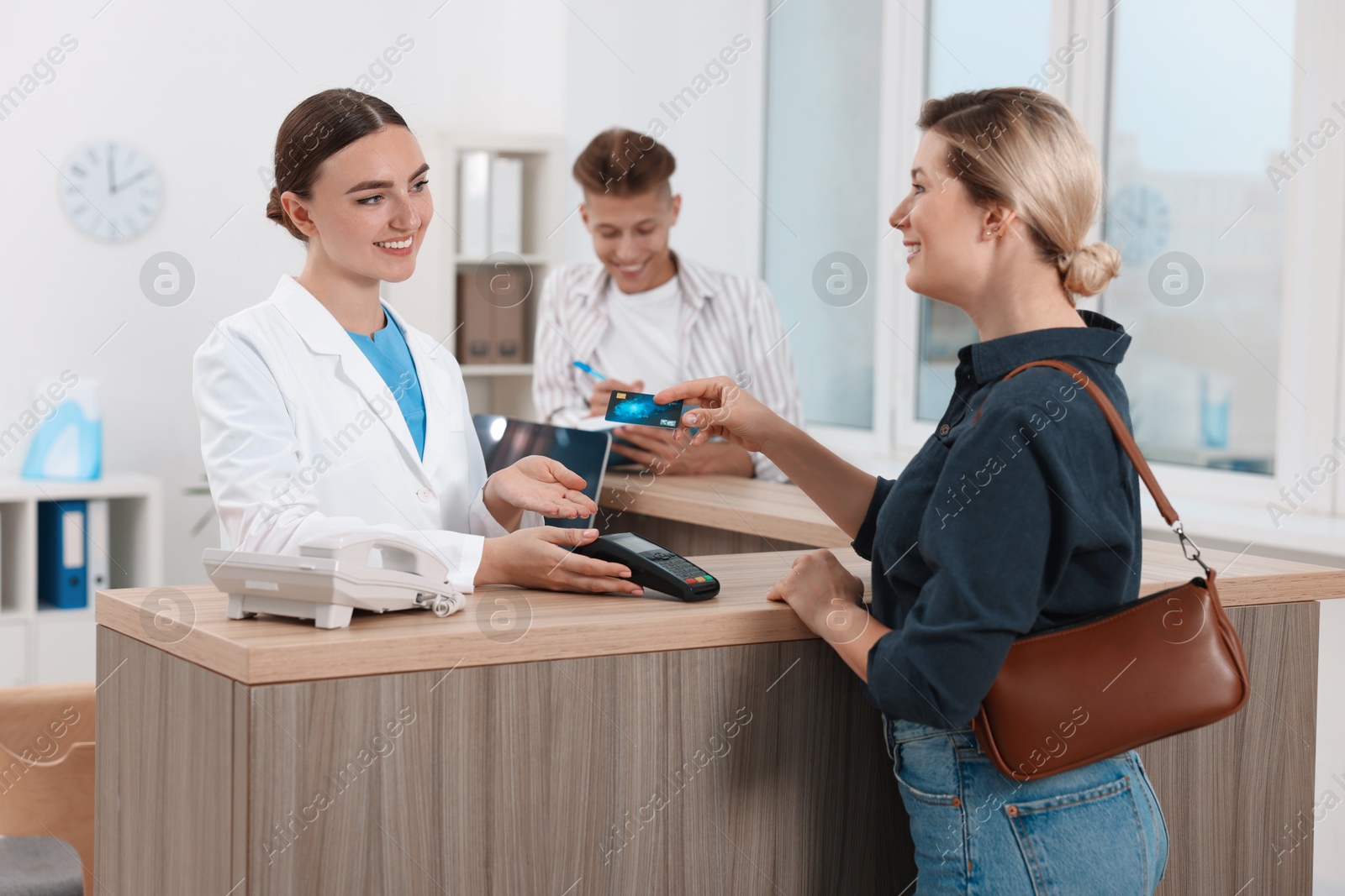 Photo of Receptionist taking payment from client via terminal at hospital