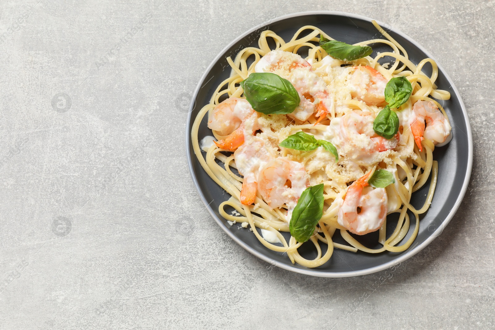 Photo of Tasty pasta with shrimps on light grey table, top view. Space for text