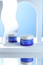 Photo of Stylish presentation of face cream in jar against light blue background