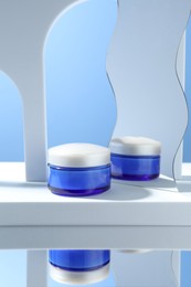 Stylish presentation of face cream in jar against light blue background