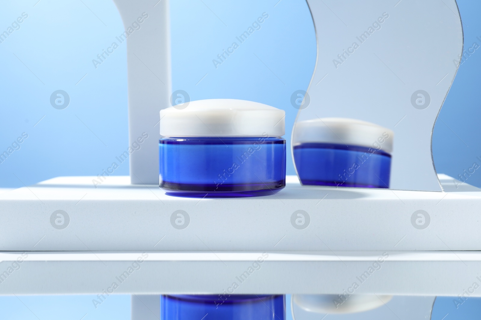 Photo of Stylish presentation of face cream in jar against light blue background