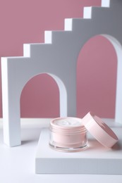 Stylish presentation of face cream in jar against pink background