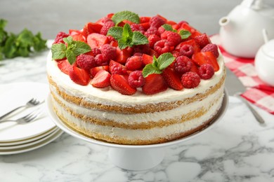 Photo of Tasty sponge cake with fresh berries and mint on white marble table, closeup