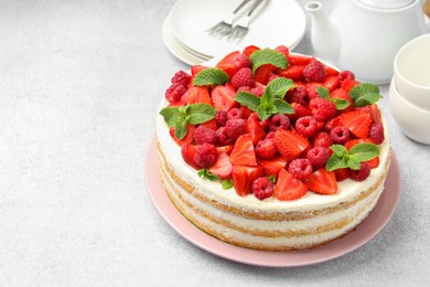 Photo of Tasty sponge cake with fresh berries and mint on light gray table, space for text