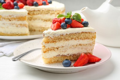 Photo of Tasty sponge cake with fresh berries and mint served on white table, closeup