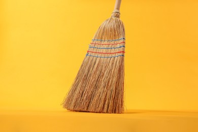 Photo of One corn straw broom on orange background