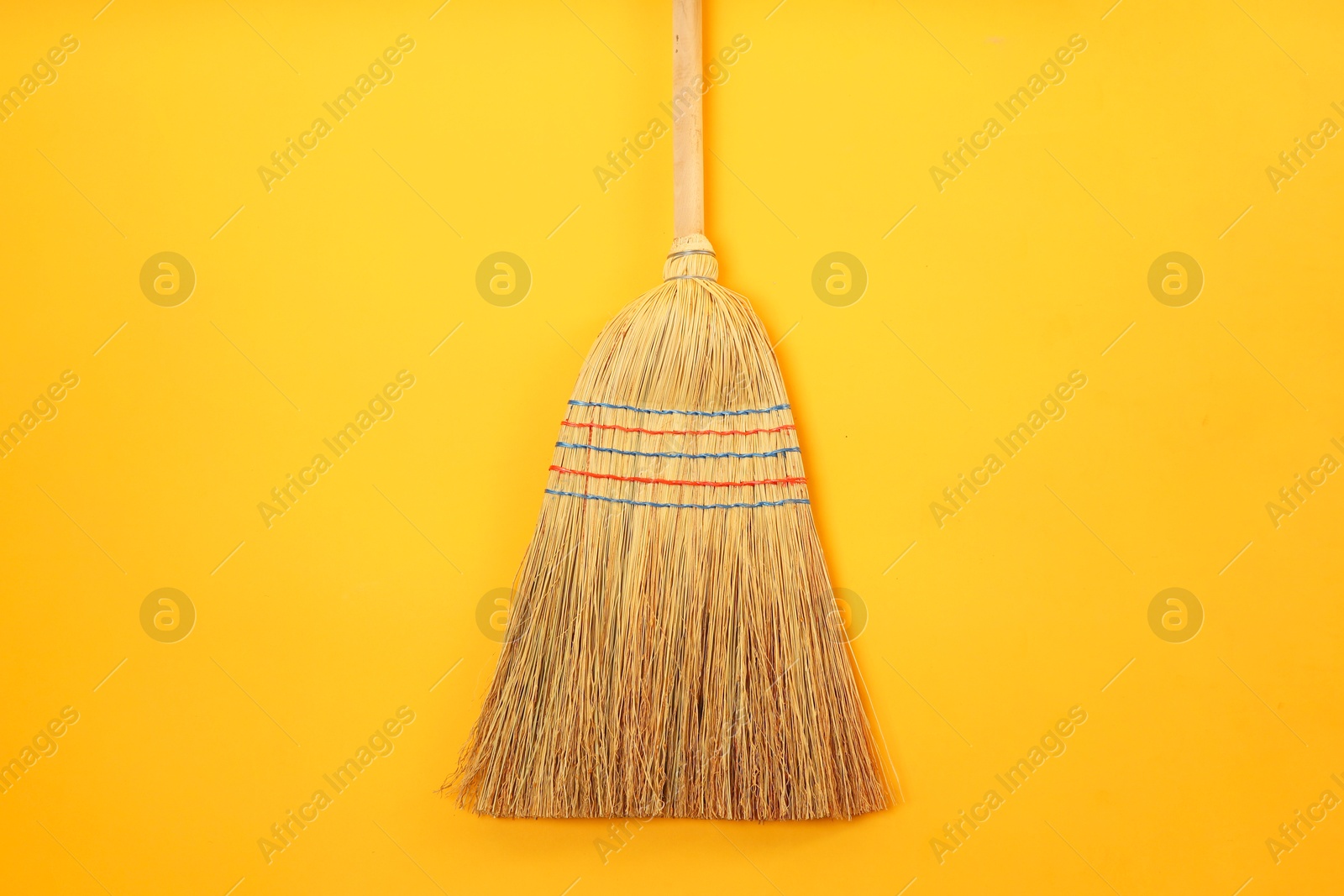 Photo of One corn straw broom on orange background, top view