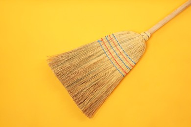 Photo of One corn straw broom on orange background, top view