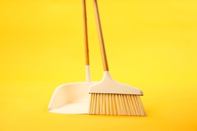 Photo of Cleaning broom and dustpan on yellow background