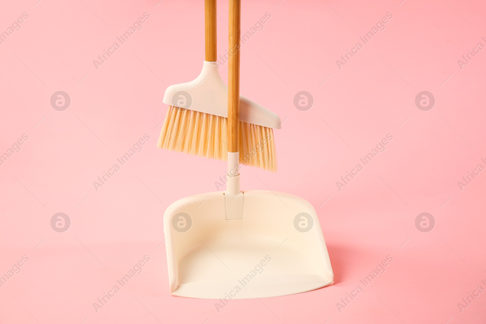 Photo of Cleaning broom and dustpan on pink background