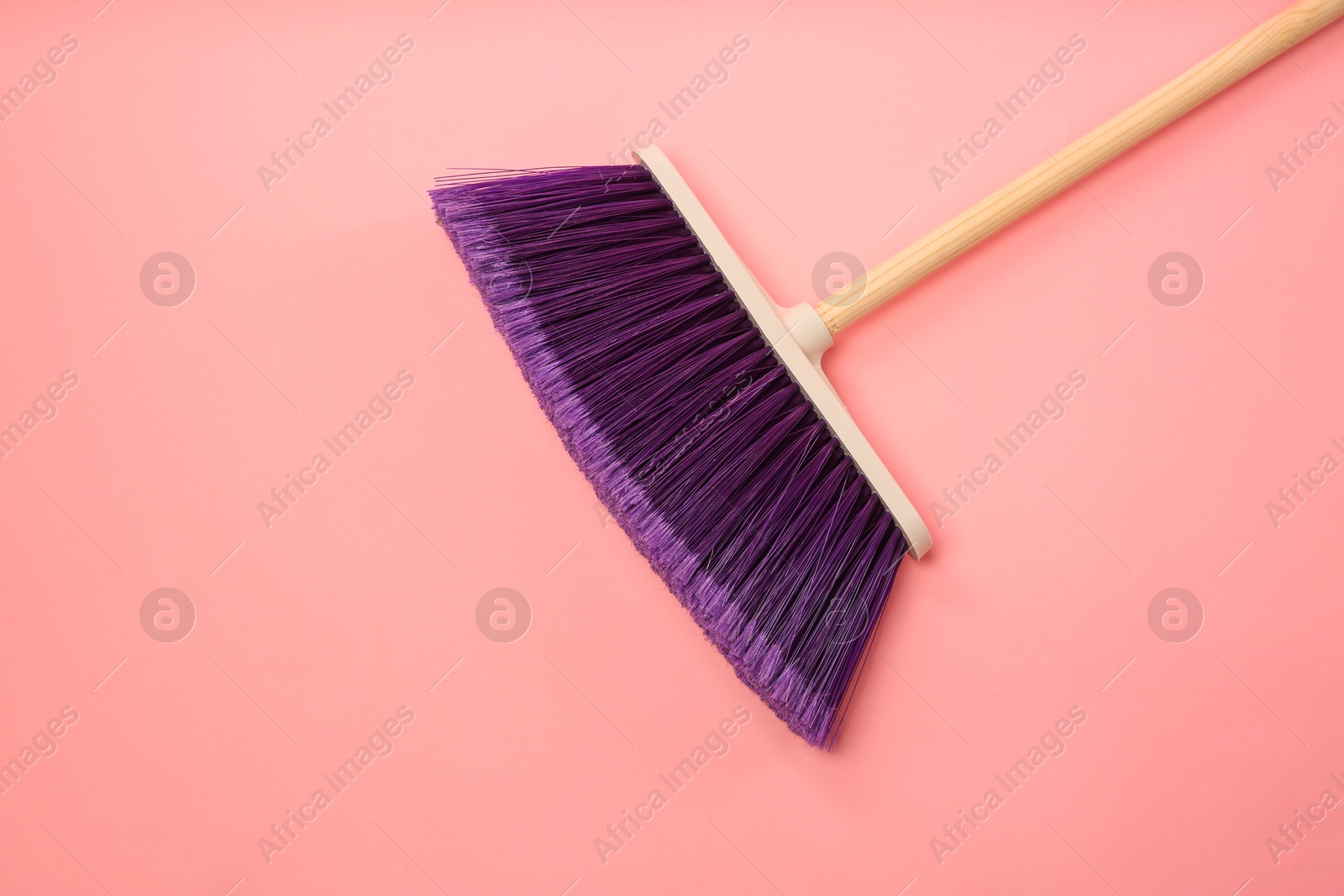 Photo of One cleaning broom on pink background, top view