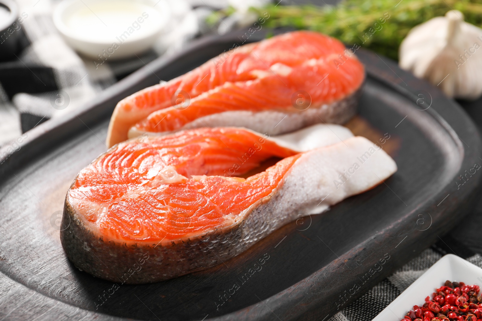 Photo of Board with fresh salmon steaks on table, closeup