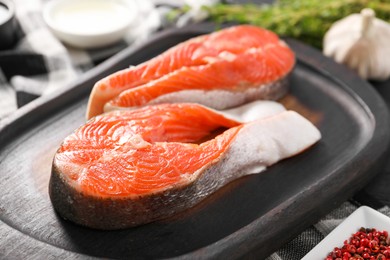 Photo of Board with fresh salmon steaks on table, closeup