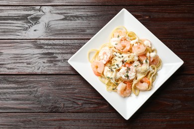 Photo of Delicious pasta with shrimps on wooden table, top view. Space for text