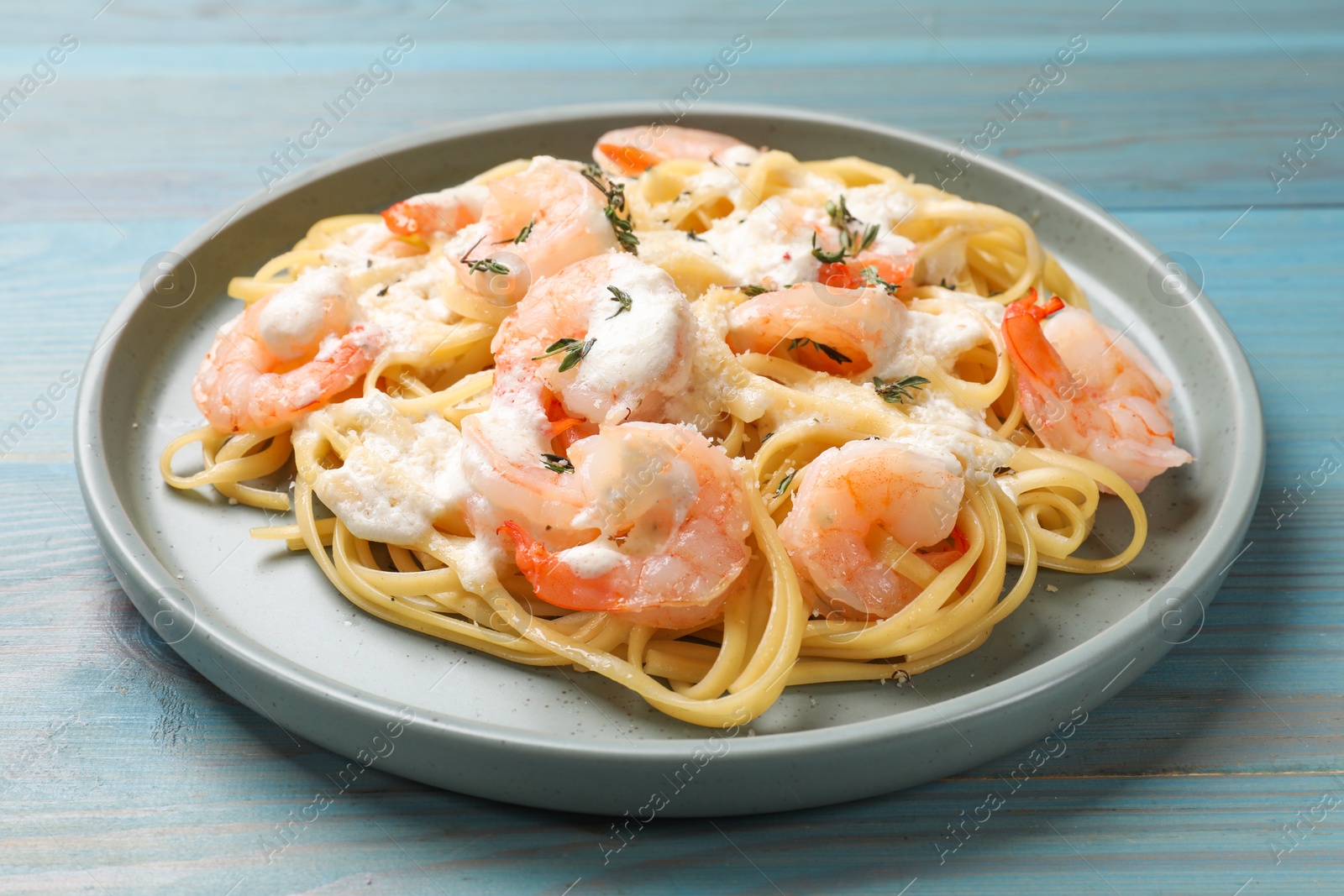 Photo of Delicious pasta with shrimps on blue wooden table, closeup