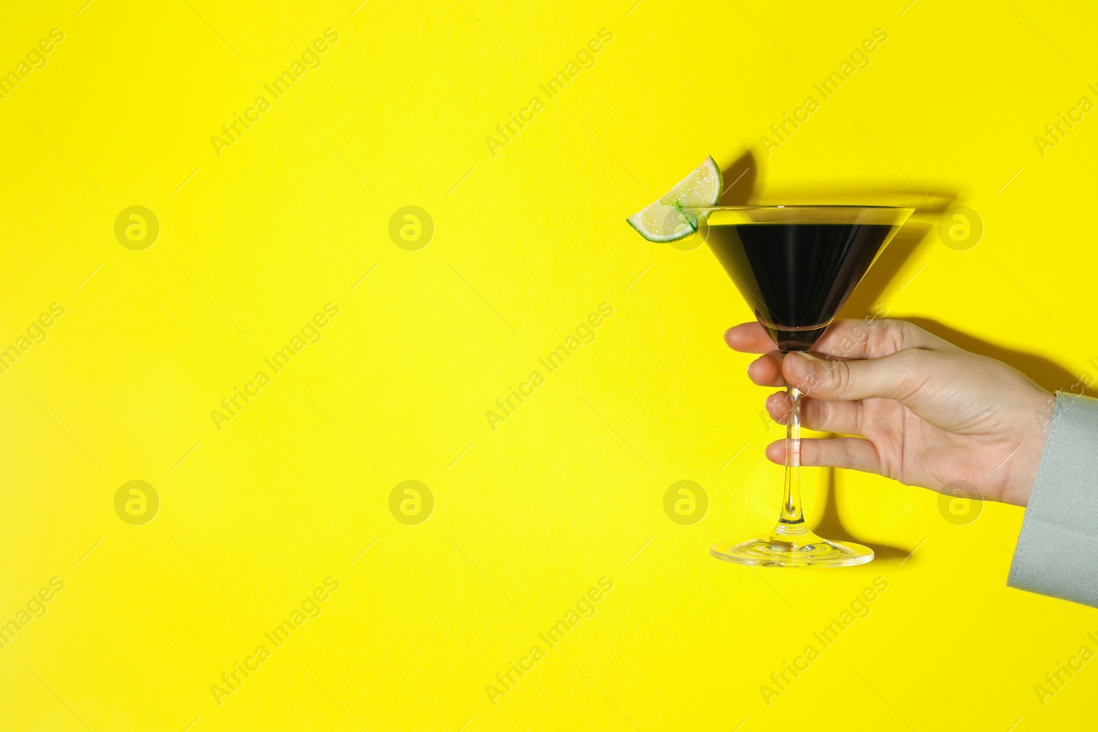 Photo of Woman with glass of refreshing cocktail on yellow background, closeup. Space for text