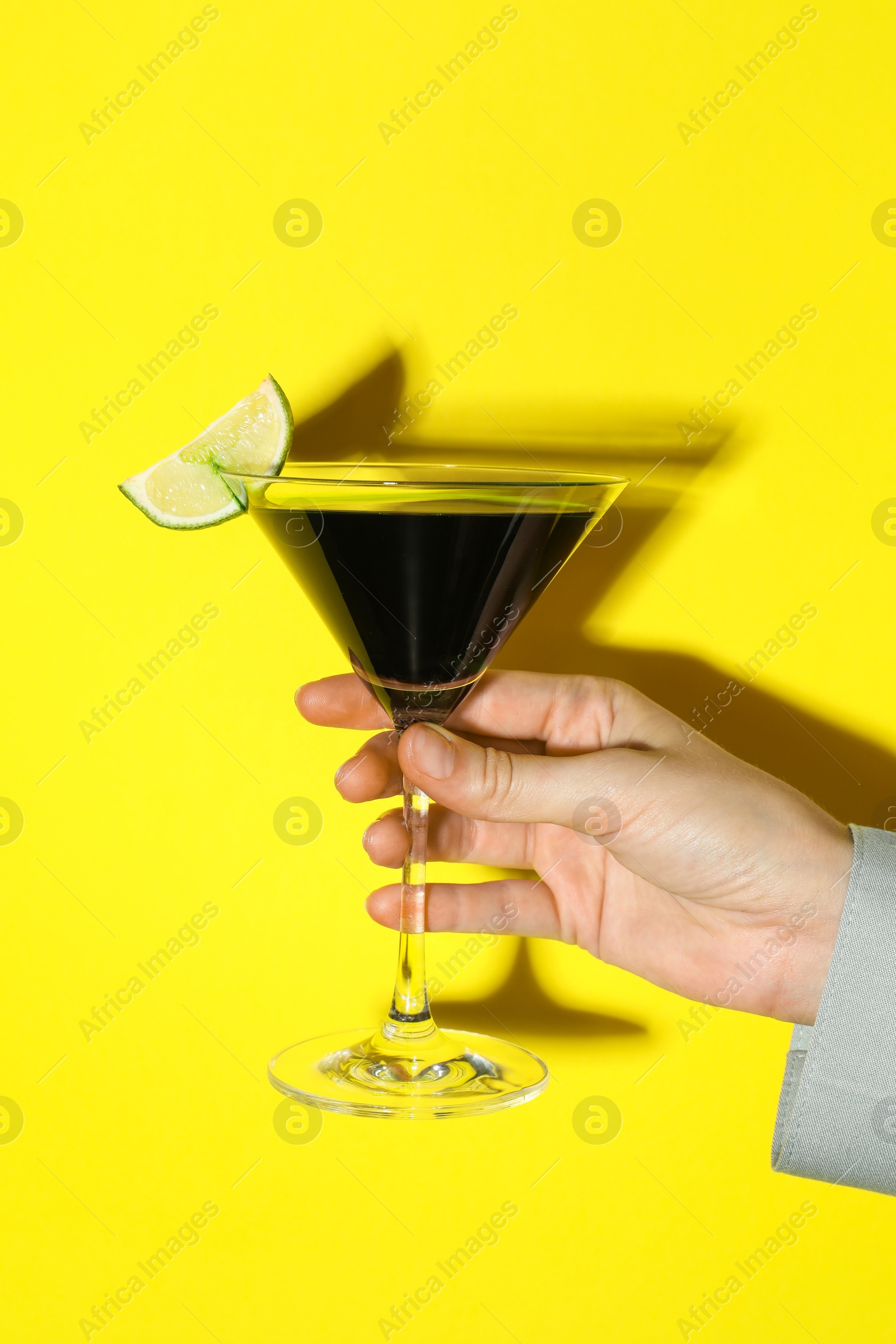 Photo of Woman with glass of refreshing cocktail on yellow background, closeup