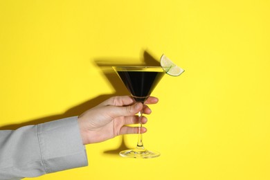 Photo of Woman with glass of refreshing cocktail on yellow background, closeup