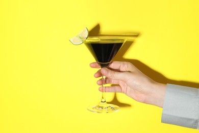 Photo of Woman with glass of refreshing cocktail on yellow background, closeup