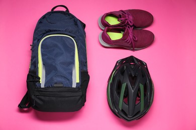 Photo of Backpack, bicycle helmet and sneakers on pink background, flat lay