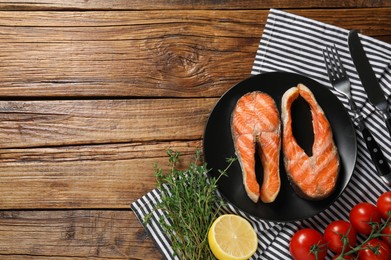 Tasty grilled salmon steaks served on wooden table, flat lay. Space for text