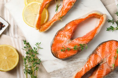 Photo of Tasty grilled salmon steaks, lemon and thyme on table, flat lay