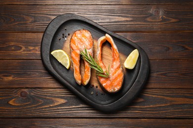 Photo of Tasty grilled salmon steaks, lemon and spices on wooden table, top view