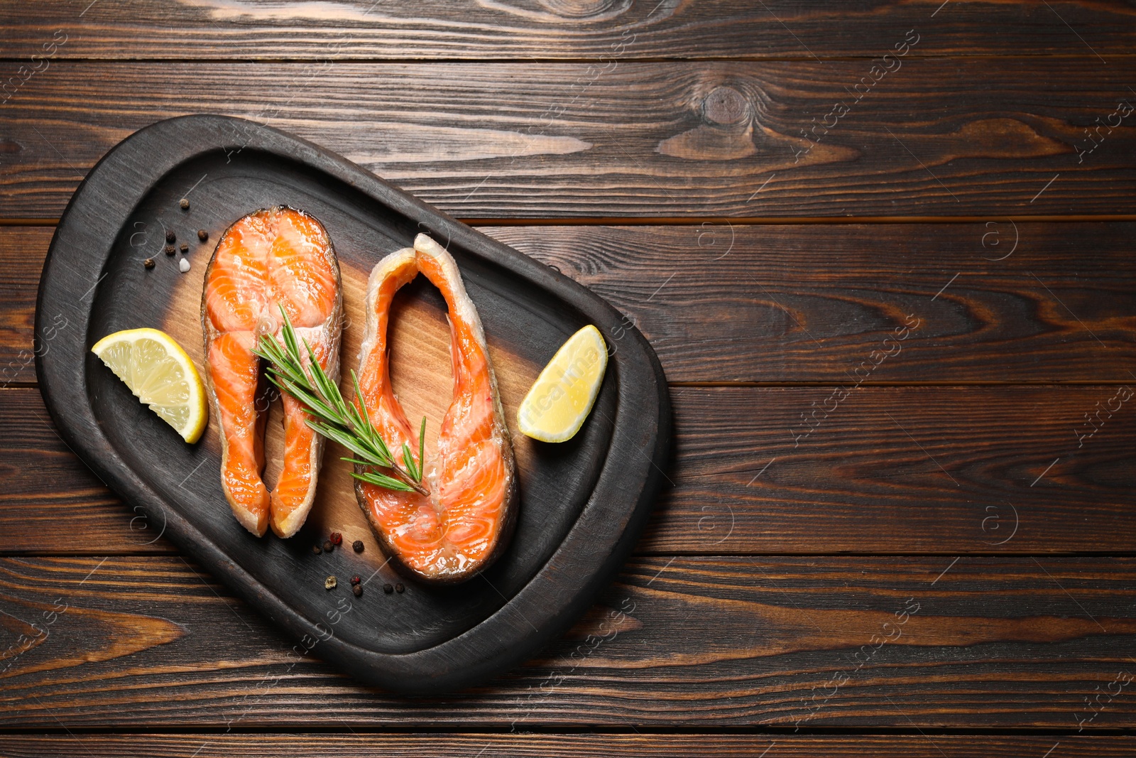 Photo of Tasty grilled salmon steaks, lemon and spices on wooden table, top view. Space for text