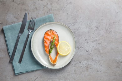 Photo of Tasty grilled salmon steak served on gray textured table, flat lay. Space for text