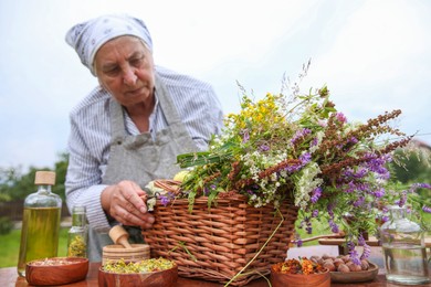 Photo of Senior woman with different ingredients for tincture outdoors, selective focus