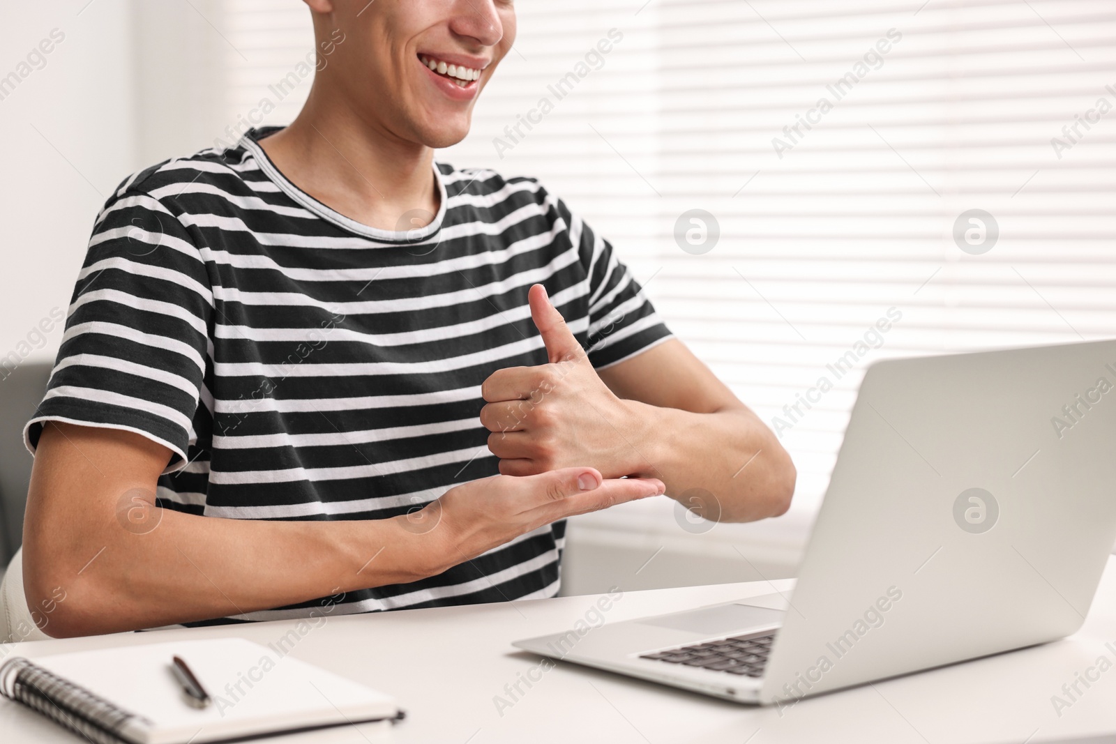 Photo of Young man using sign language during video call indoors, closeup