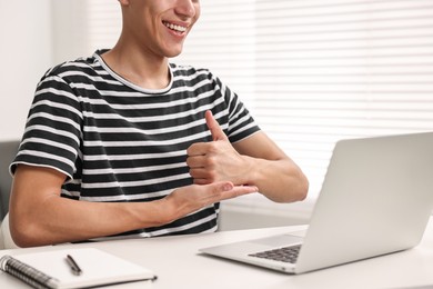 Young man using sign language during video call indoors, closeup