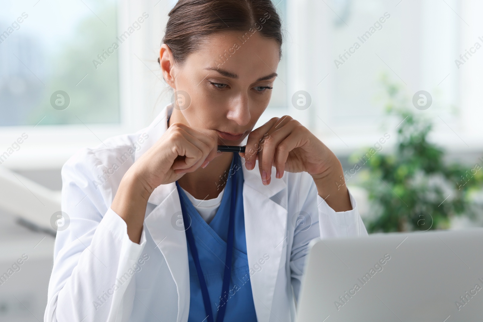 Photo of Nurse in medical uniform with pen indoors