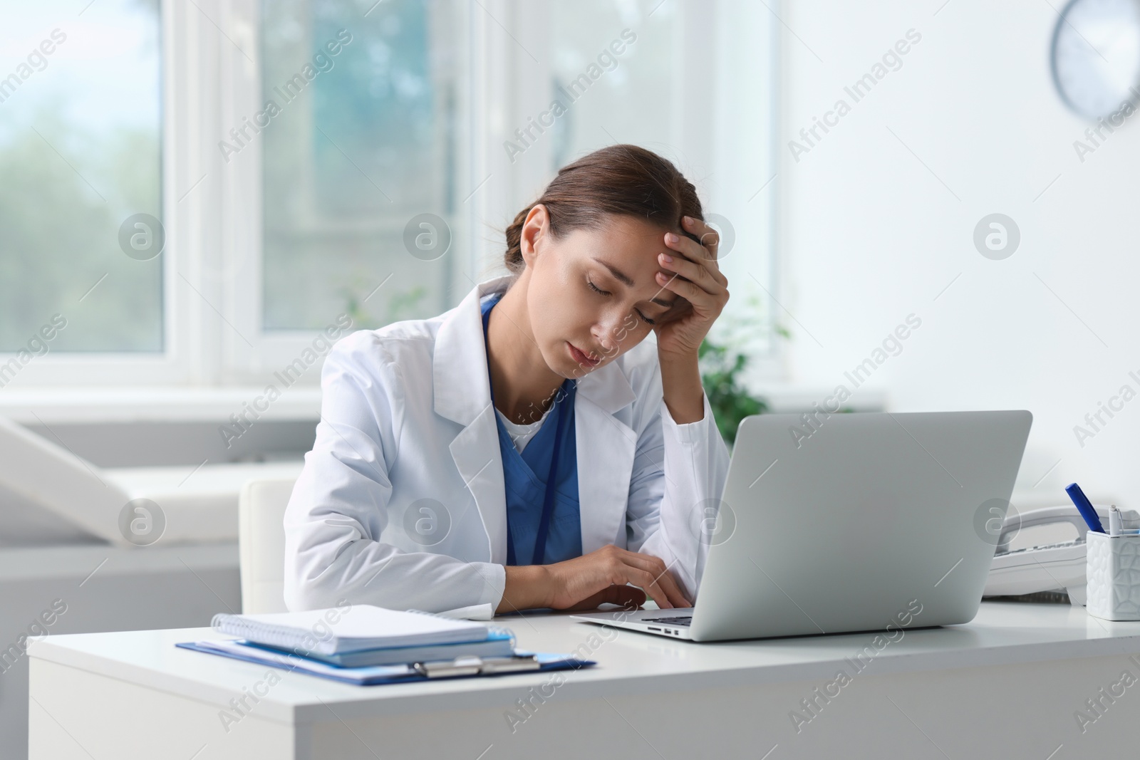 Photo of Tired nurse sleeping at white table in clinic