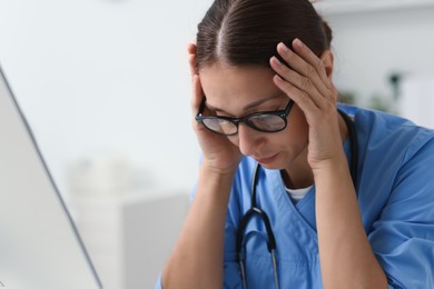 Tired nurse with stethoscope in clinic, space for text