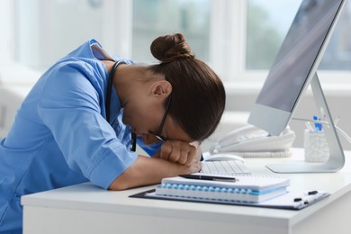 Tired nurse at white table in clinic