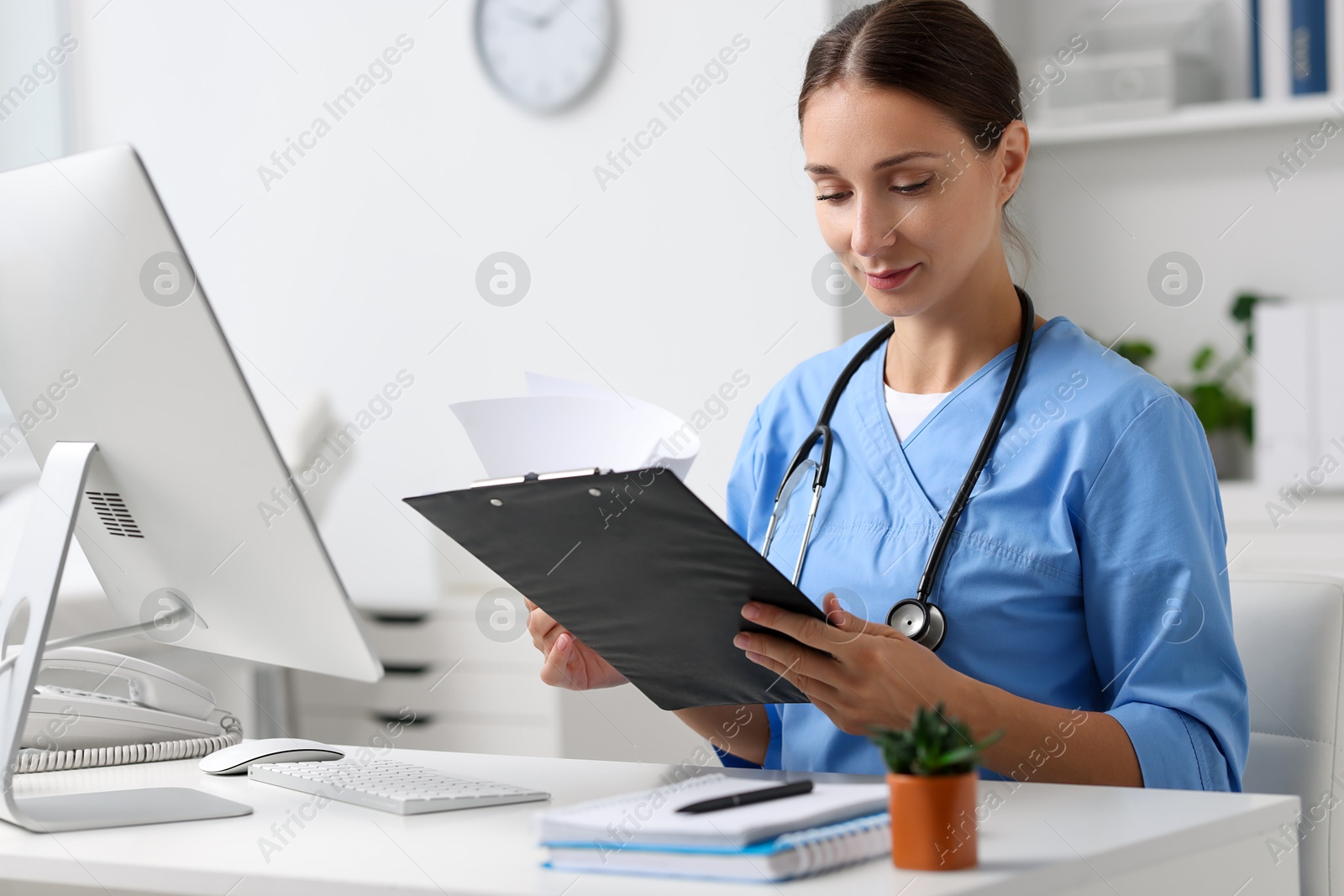 Photo of Nurse with clipboard at white table in clinic