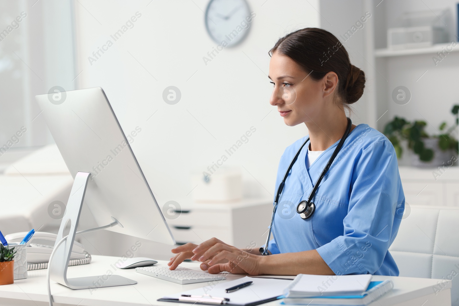 Photo of Nurse working on computer at table in clinic