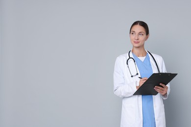 Nurse in medical uniform with stethoscope and clipboard on grey background, space for text