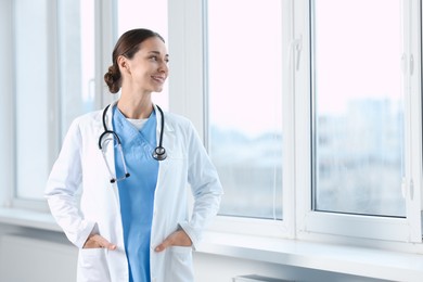 Nurse in medical uniform with stethoscope near window indoors